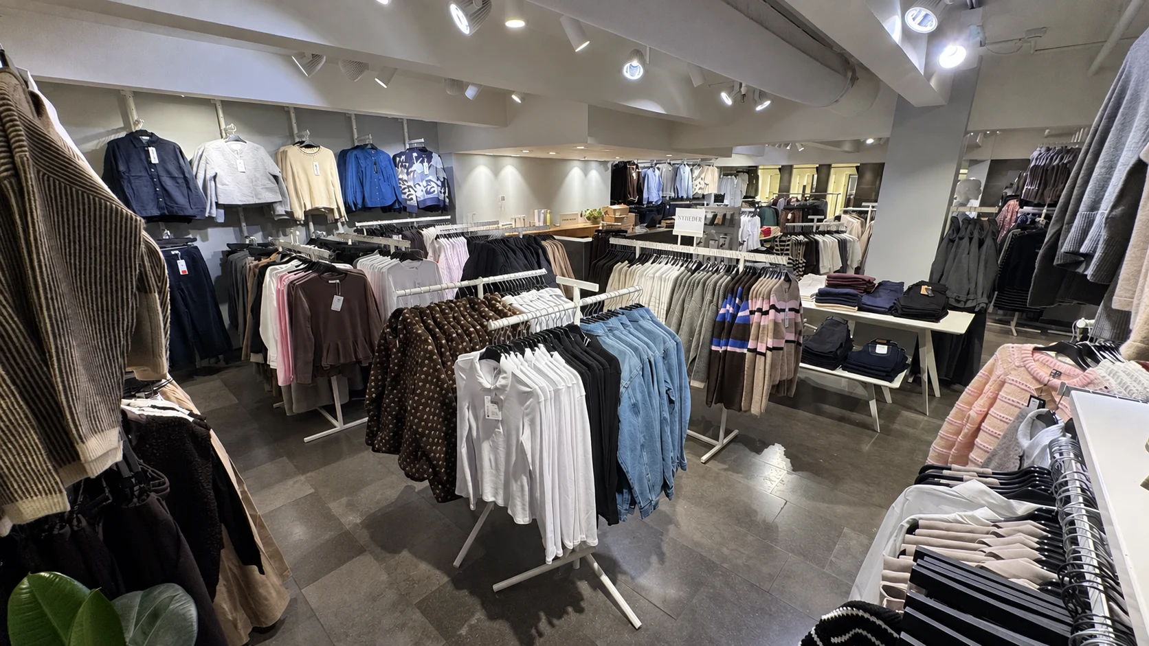 Bredt kig gennem NOYAs rummelige butik med tøjstativer og udvalg af dametøj